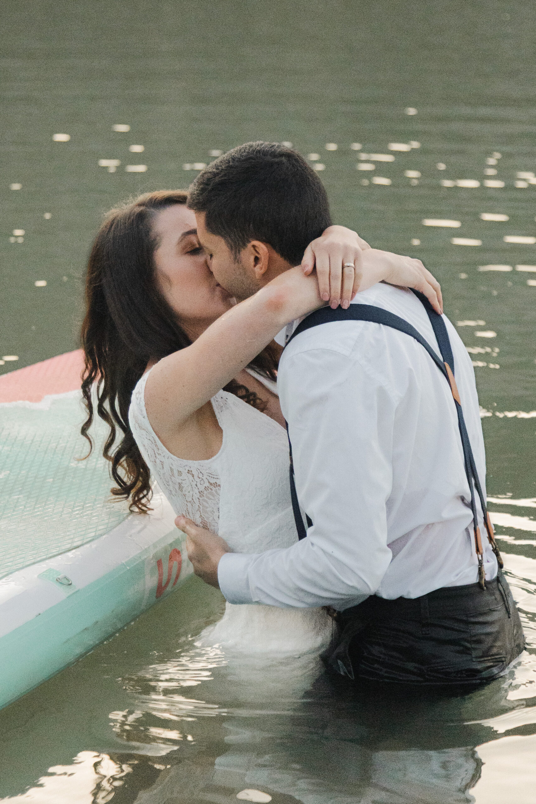 Romantic paddle boarding elopement photo of a couple kissing in a mountain lake during an intimate elopement in Canmore, Alberta, capturing an adventurous paddle board elopement in Canmore.