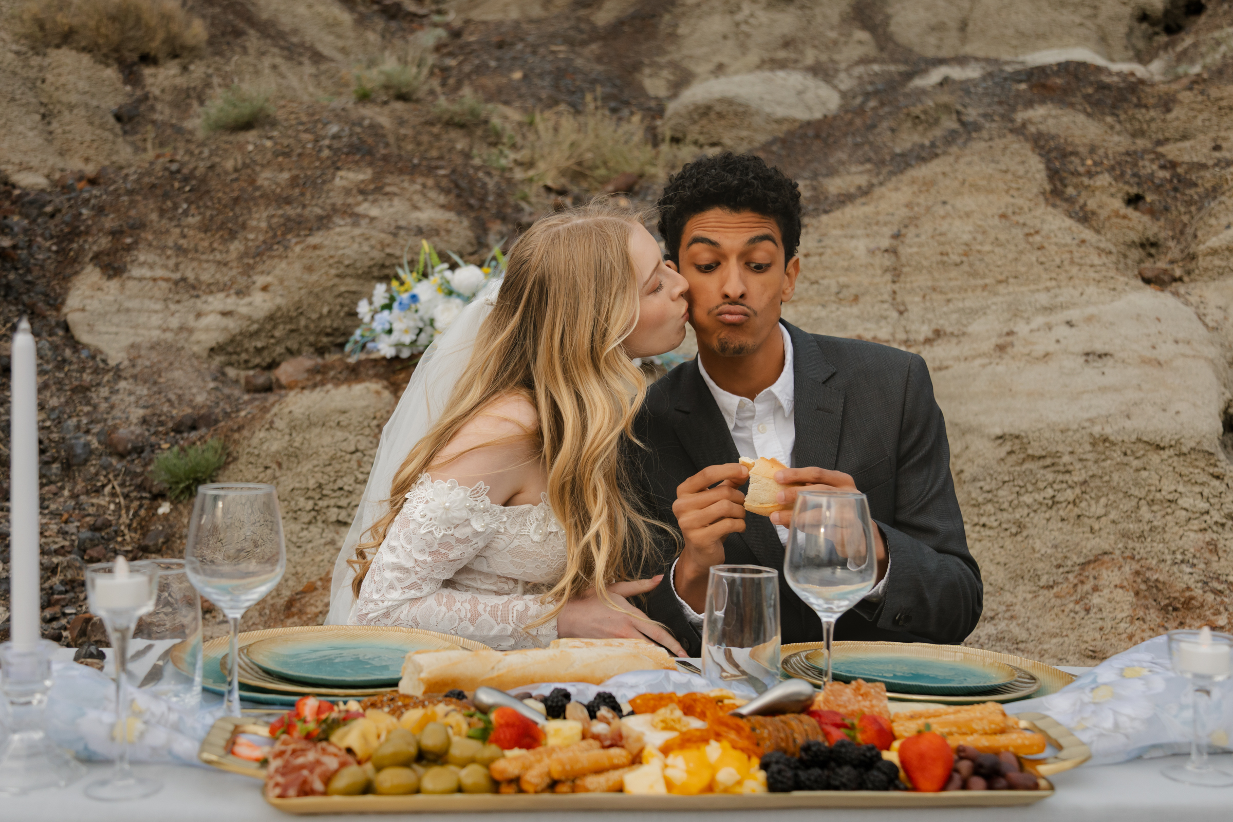 A bride and groom enjoying a sunset picnic on a blanket in the Drumheller Badlands, featuring an editorial charcuterie spread during their Alberta destination elopement.