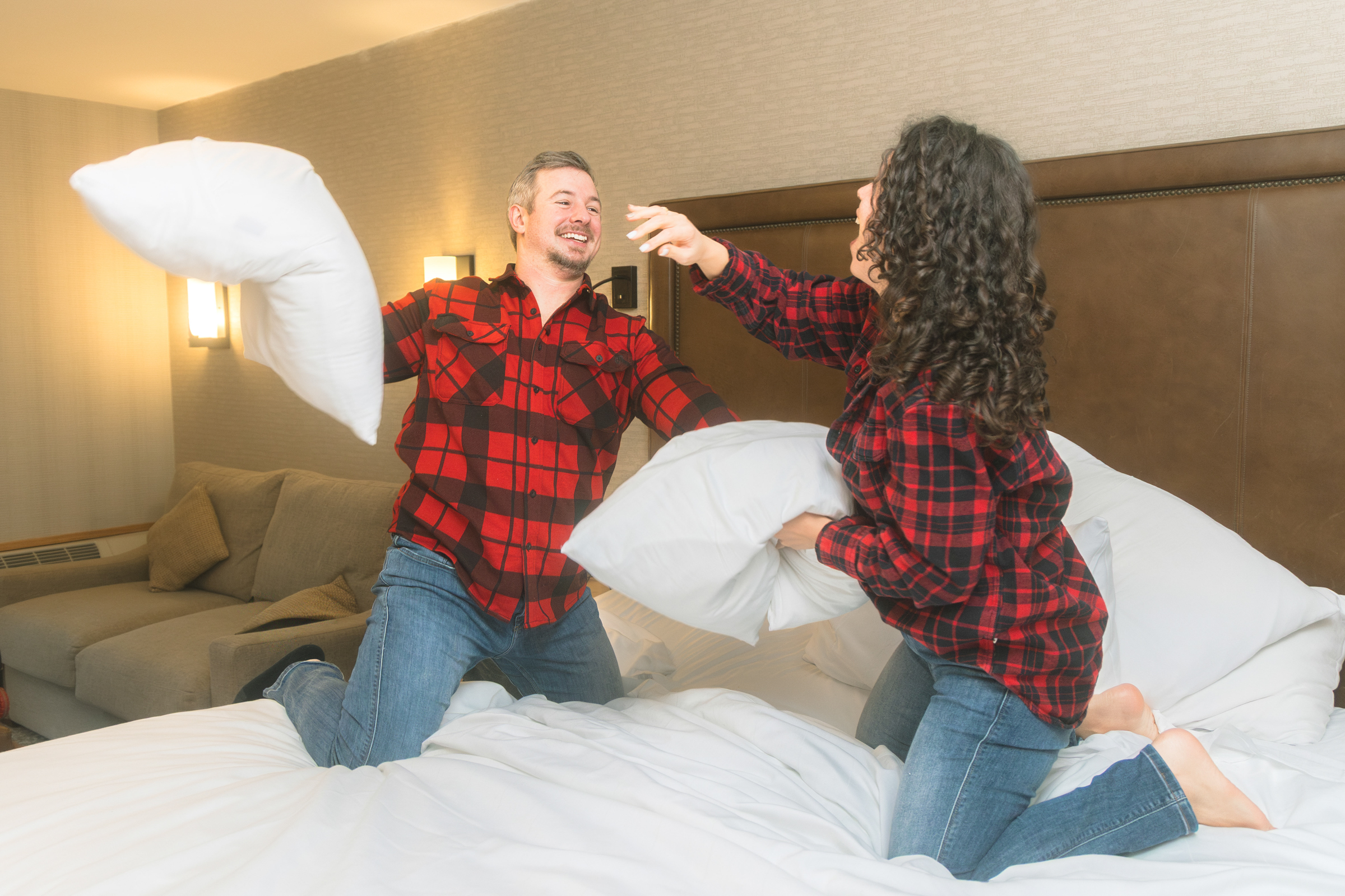 A couple having a playful pillow fight during their elopement morning at Moose Hotel & Suites in Banff, capturing a candid and intentional moment of connection.
