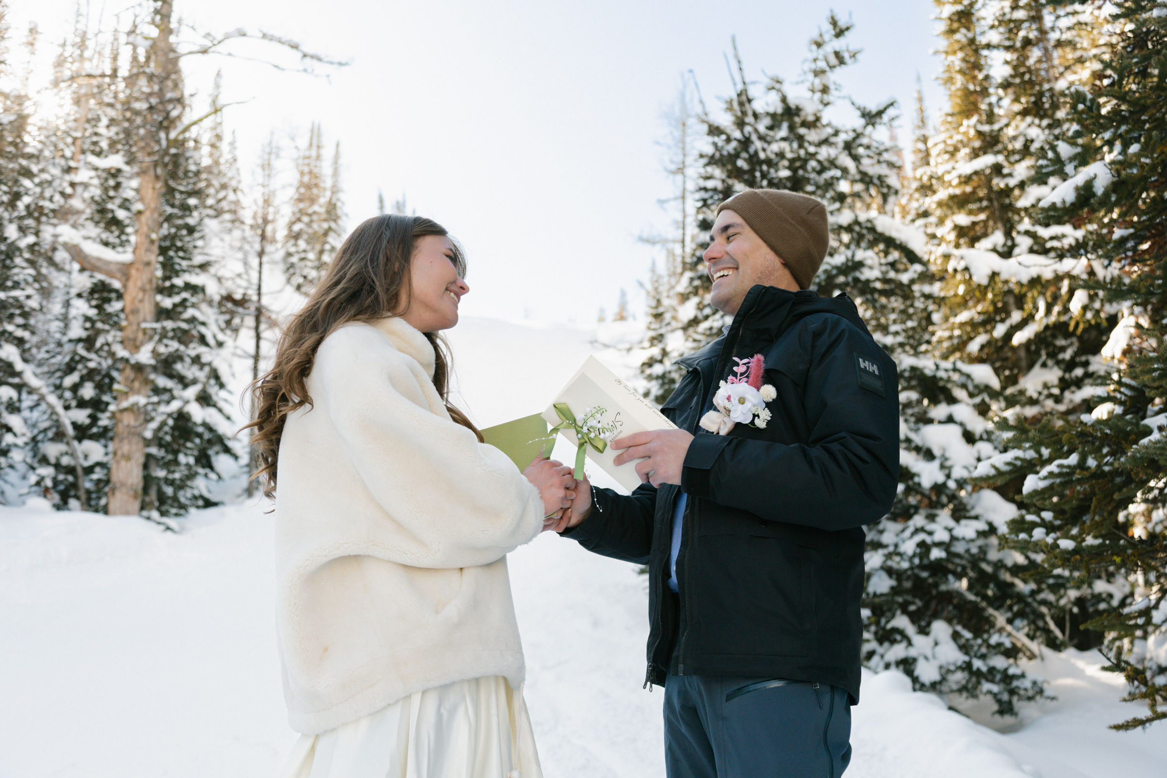 A couple in winter wedding attire exchanging vows in the snow at Sunshine Village Ski Resort, surrounded by the peaks of Banff National Park.